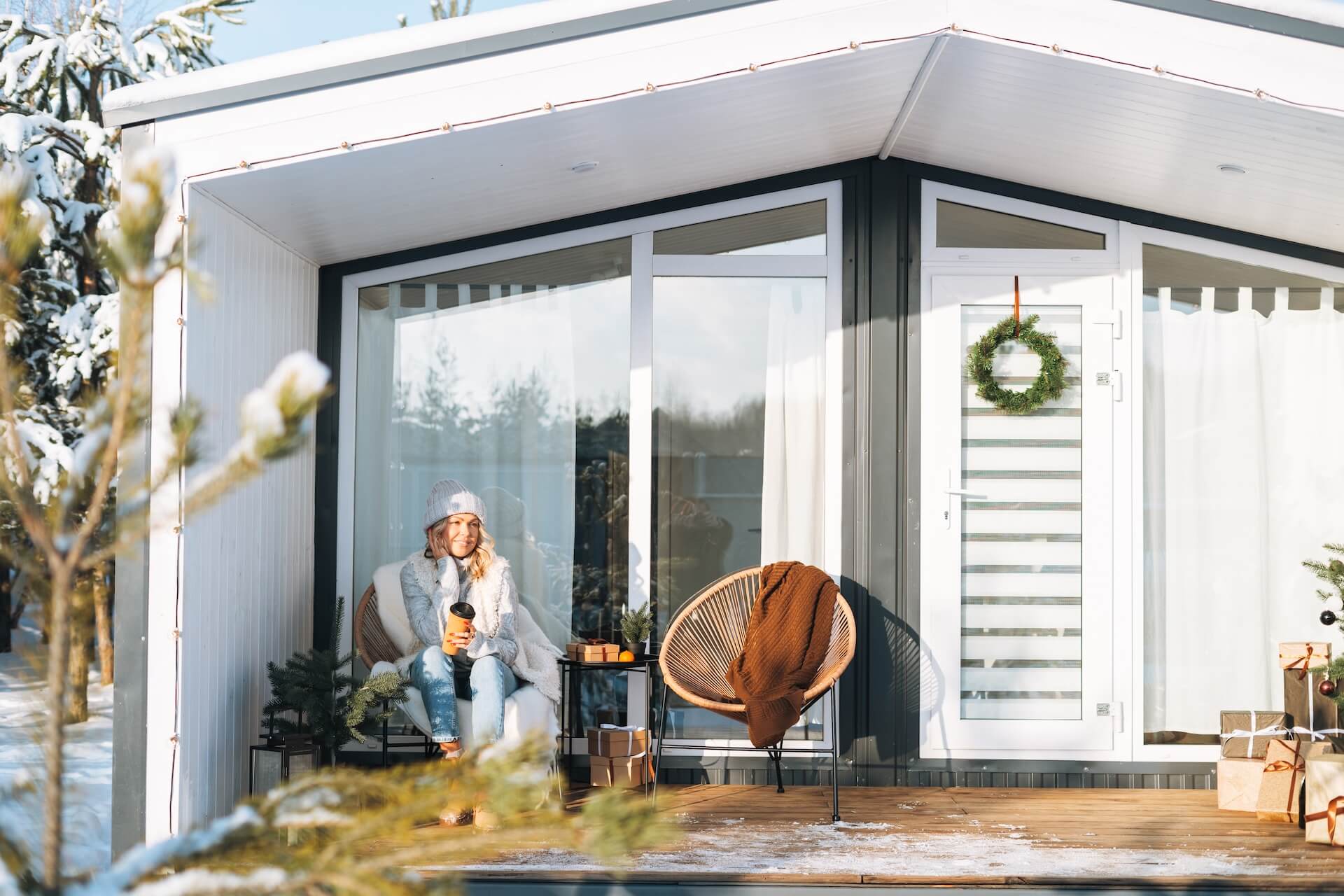 Woman sitting with a coffee cup in front of house built and designed with modern Scandinavian architecture | Featured image for the Modern Scandinavian Architecture Blog by Clements Clarke Architects.